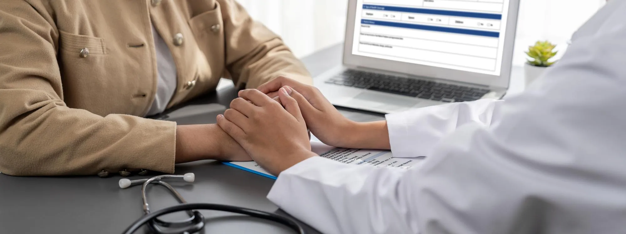 A healthcare professional holding a patient's hands during a consultation, representing compassionate guidance and assistance through Patient Assistance Programs.