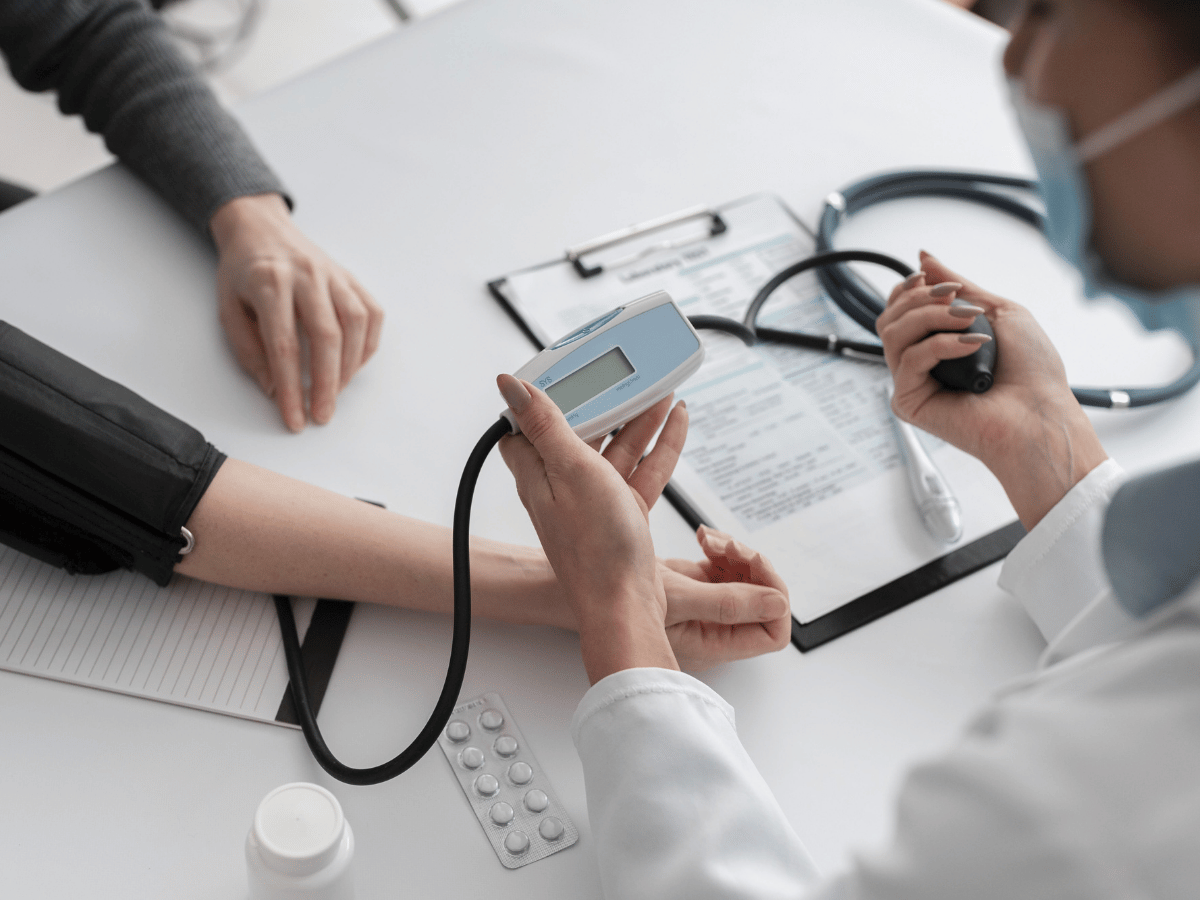 Healthcare professional measuring a patient’s blood pressure during a clinic visit, illustrating Chronic Condition Care Management Services and ongoing health monitoring.