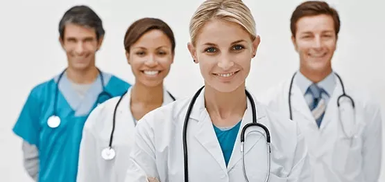 A diverse team of four smiling medical professionals, including doctors in white coats and nurses in blue scrubs, representing Central Health Solutions healthcare services.