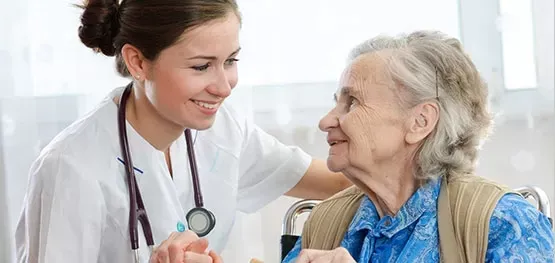 Healthcare worker with stethoscope helping senior woman patient, compassionate elderly care in hospital or clinic environment