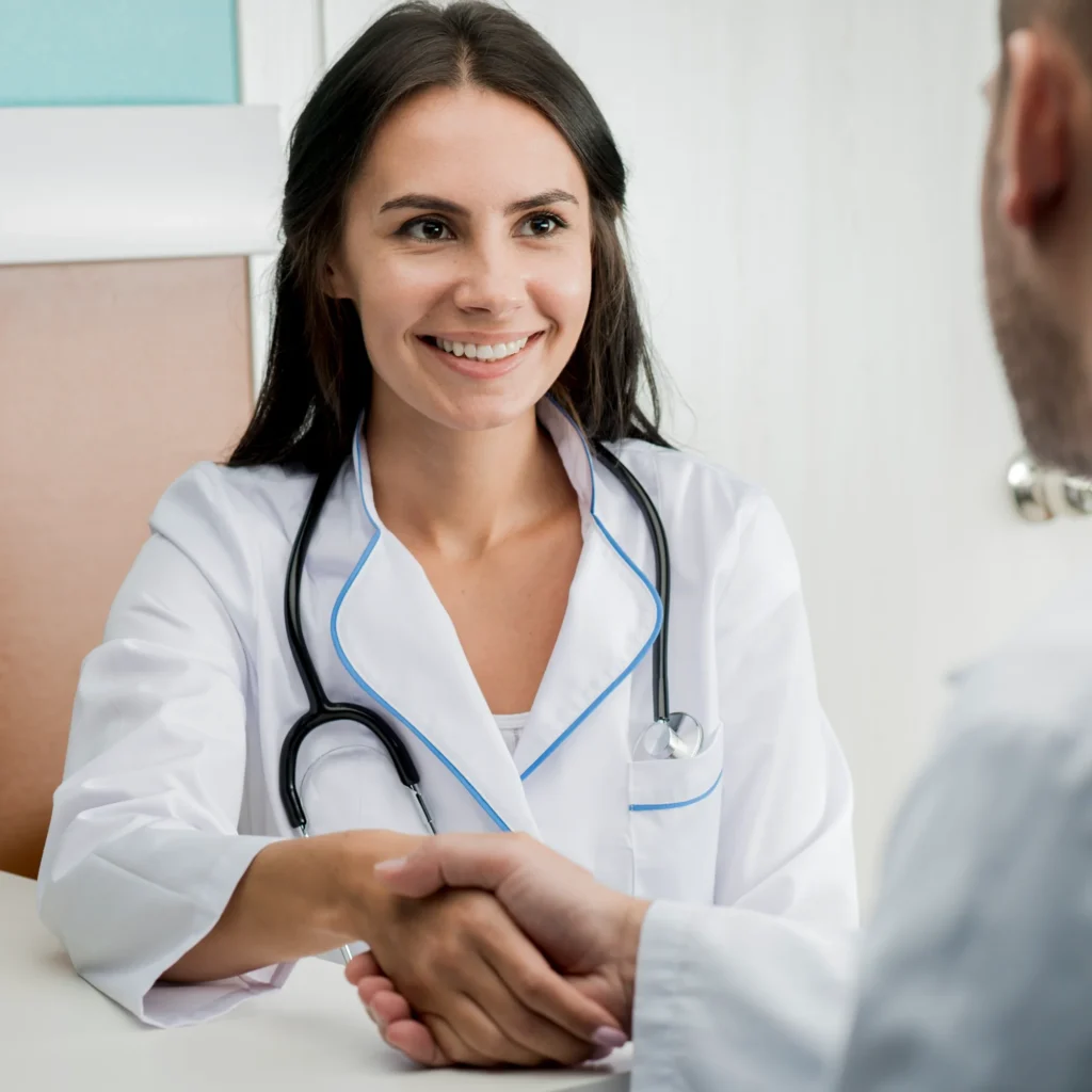 Medication AdhSmiling female doctor in a white coat with a stethoscope shaking hands with a male patient in a bright, modern clinic at Central Health Solutions, representing friendly, professional healthcare consultation and patient care. erence Assistance