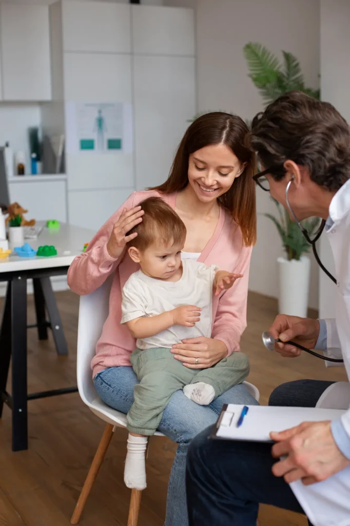 Smiling mother holding her child during a doctor's visit, reflecting Central Health Solutions' patient-centered care and family health monitoring services