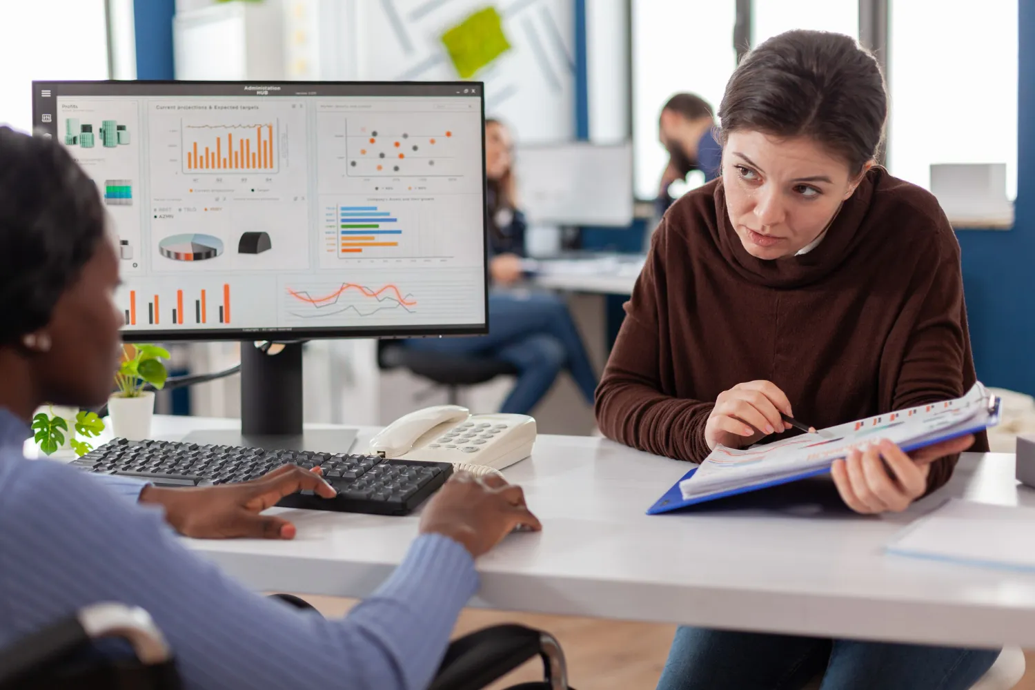 Healthcare administrators reviewing analytics dashboard and financial reports for MIPS reporting services and compliance management