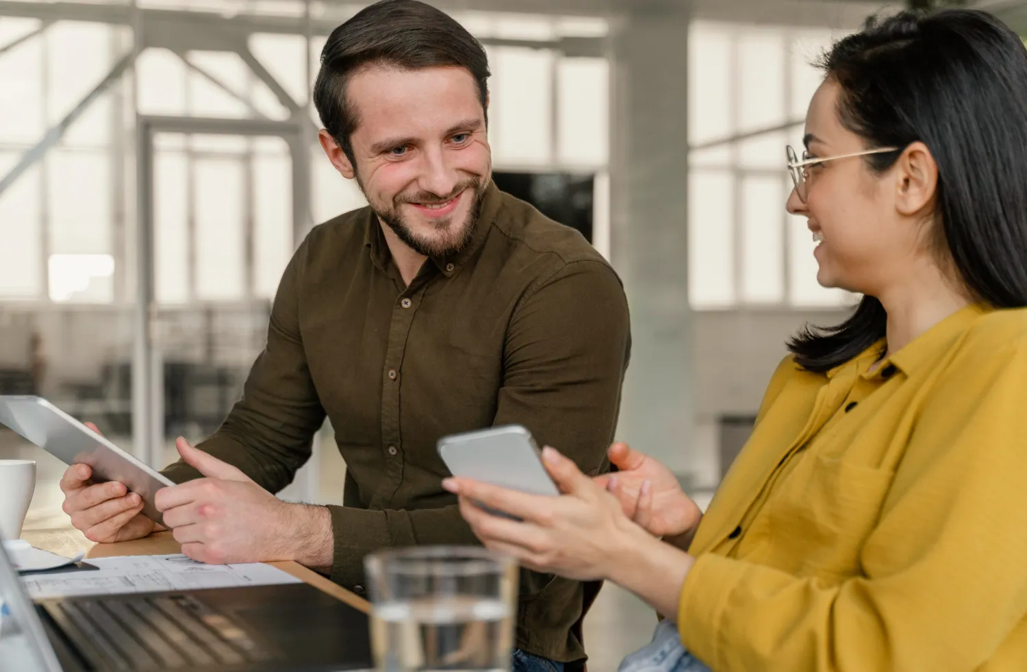 Healthcare and administrative professionals discussing patient referral management solutions using digital devices, improving referral management services and care coordination.