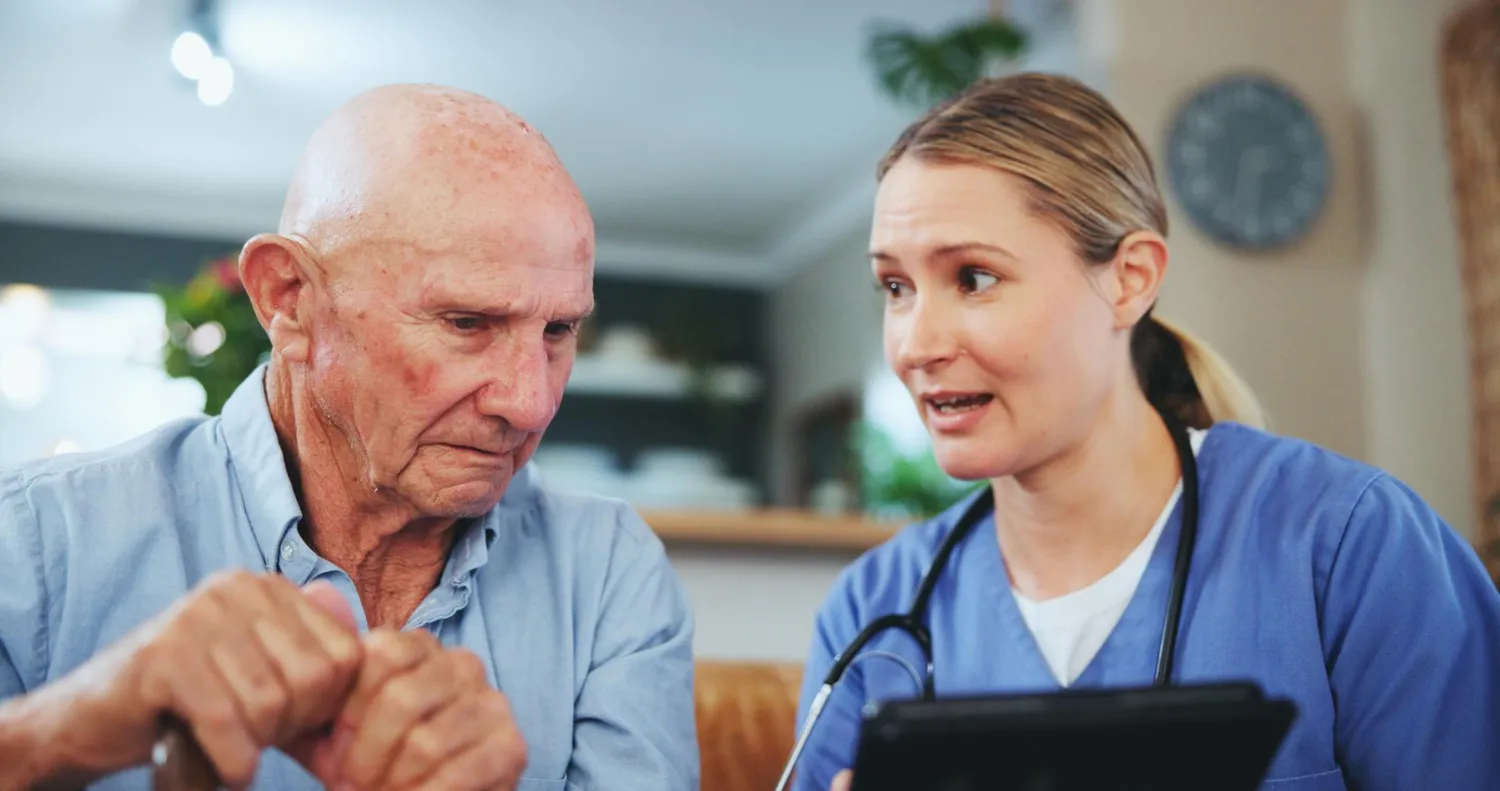 Healthcare provider reviewing a care plan with an older adult using a tablet, demonstrating continuity of care optimization with coordinated follow-up, patient education, and transitional care support after treatment.