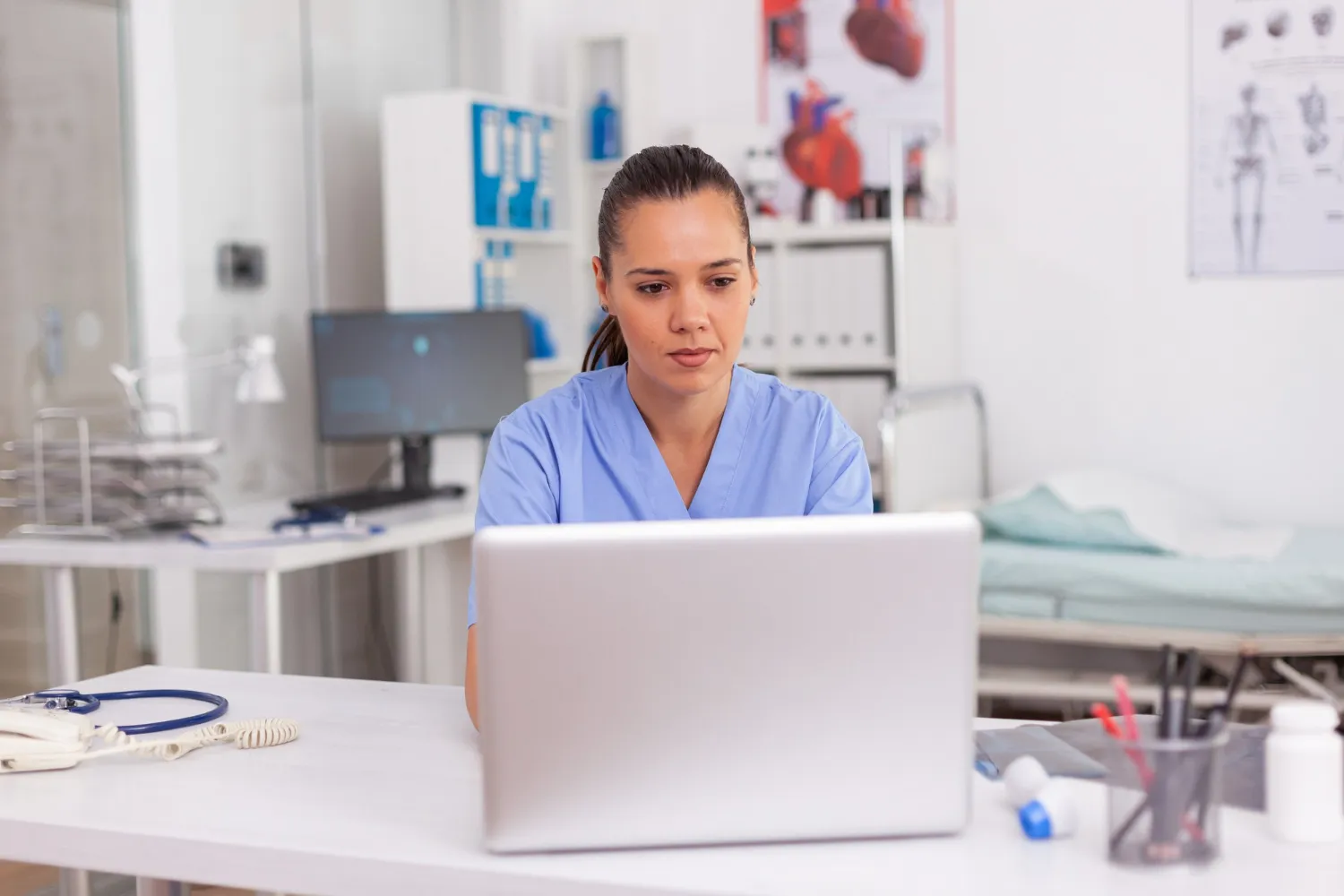 Healthcare professional reviewing patient information remotely using a Patient Monitoring Program to deliver Remote Patient Support Services and Remote Wellness Monitoring.