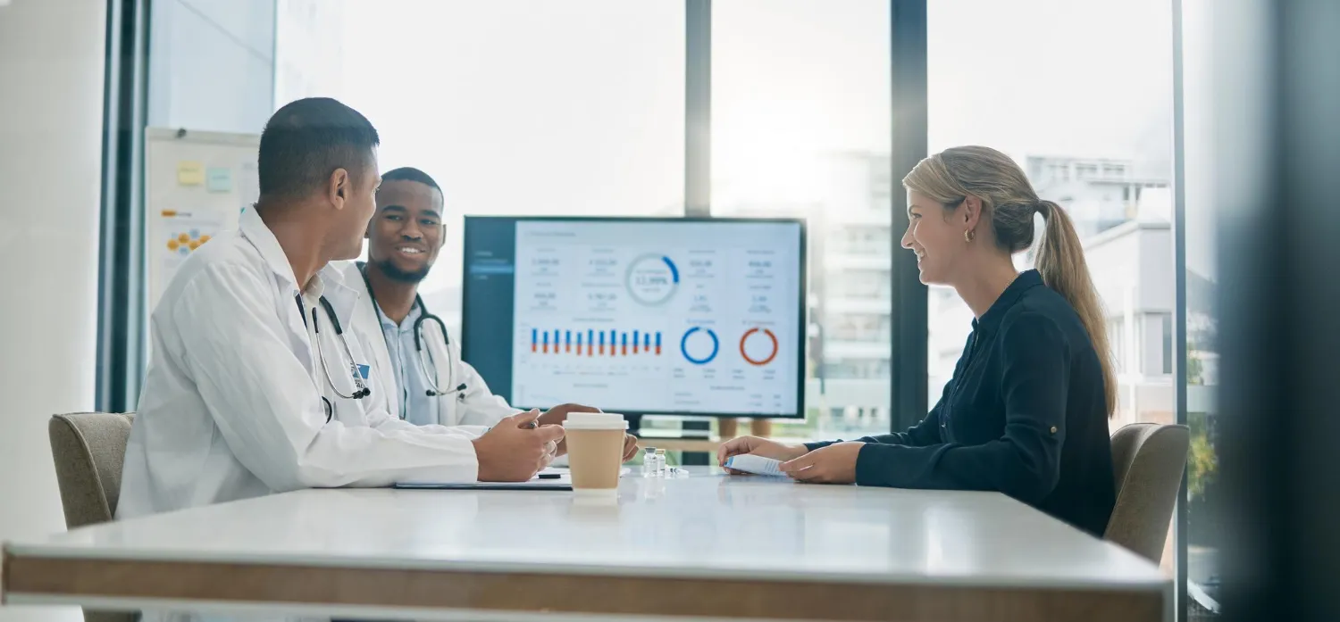 Healthcare professionals meeting with a business representative to review performance reports and discuss healthcare revenue cycle management services.